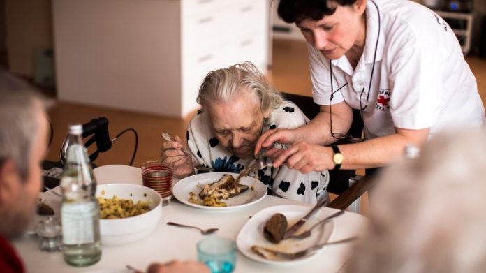 Eine Altenpflegerin hilft einer Bewohnerin beim Essen.